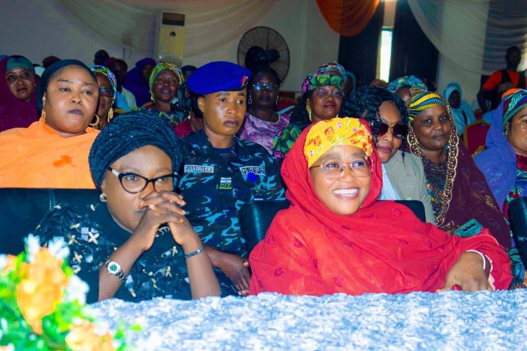 Women in colourful headscarves seated in the front rows of a hall.
